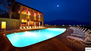 Ein Poolbereich mit Liegestühlen, ein mehrgeschossiges Gebäude und ein Nachthimmel.
