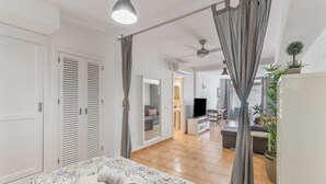 A bedroom with a bed, curtains, a ceiling fan, and a view into the living area. - Vacation Studio 'Vv Ancla' with Mountain View, Wi-Fi and Air Conditioning (Puerto de Mogán)