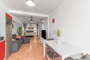 A modern kitchen with a refrigerator, microwave, and stove, a dining area with a white table and chairs, and a living area with a sofa and TV. - Vacation Studio 'Vv Ancla' with Mountain View, Wi-Fi and Air Conditioning (Puerto de Mogán)