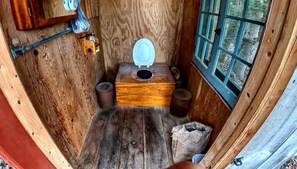 Una cabaña de madera con un inodoro, una ventana y una puerta.