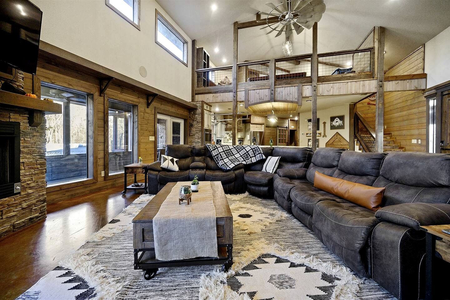 A spacious living room with a fireplace, a large sectional sofa, and a high ceiling with exposed beams.