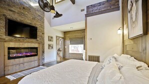 Quarto com lareira, uma cama grande e vista para o exterior.