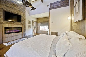 A bedroom with a fireplace, a large bed, and a view of the outdoors. - Stunning Cabin with Games Perfect for Families in Broken Bow, Oklahoma (Broken Bow)
