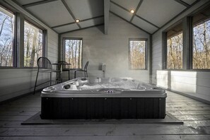 Ein Whirlpool in einem Zimmer mit großen Fenstern, Holzboden und einer Decke mit freiliegenden Balken.