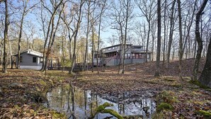 Uma cabana rodeada por árvores e um pequeno lago.