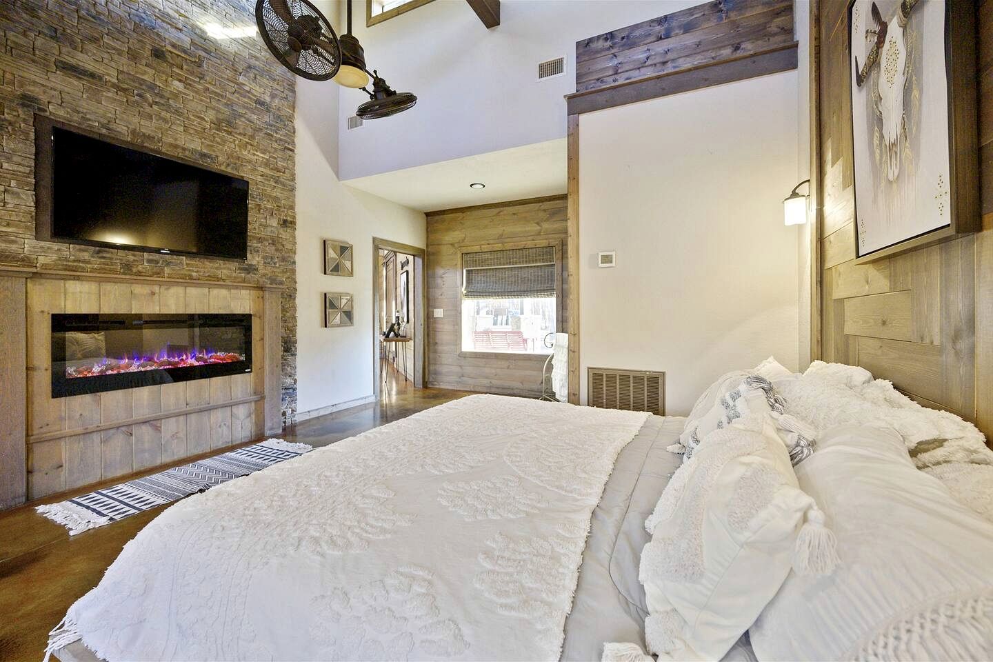 Un dormitorio con chimenea, una cama grande y vistas al exterior.
