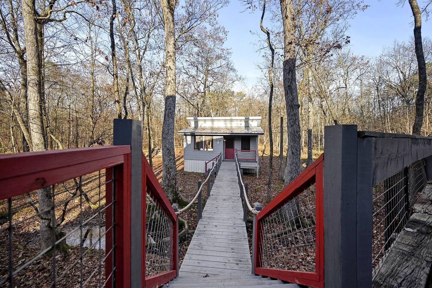 A wooden bridge leading to a cabin in a forest.