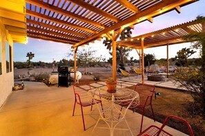 An outdoor patio with a pergola, seating, and a barbecue grill. - Yucca Valley Wonderland: Embark on a Unique Desert Adventure (Yucca Valley)
