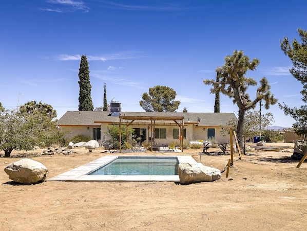 Ein Haus mit Pool, Terrasse und Wüstenbepflanzung.
