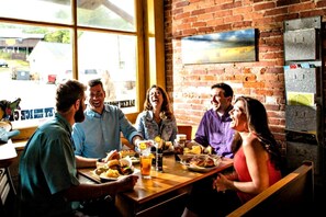 A group of people dining at a restaurant with a brick wall and large windows.