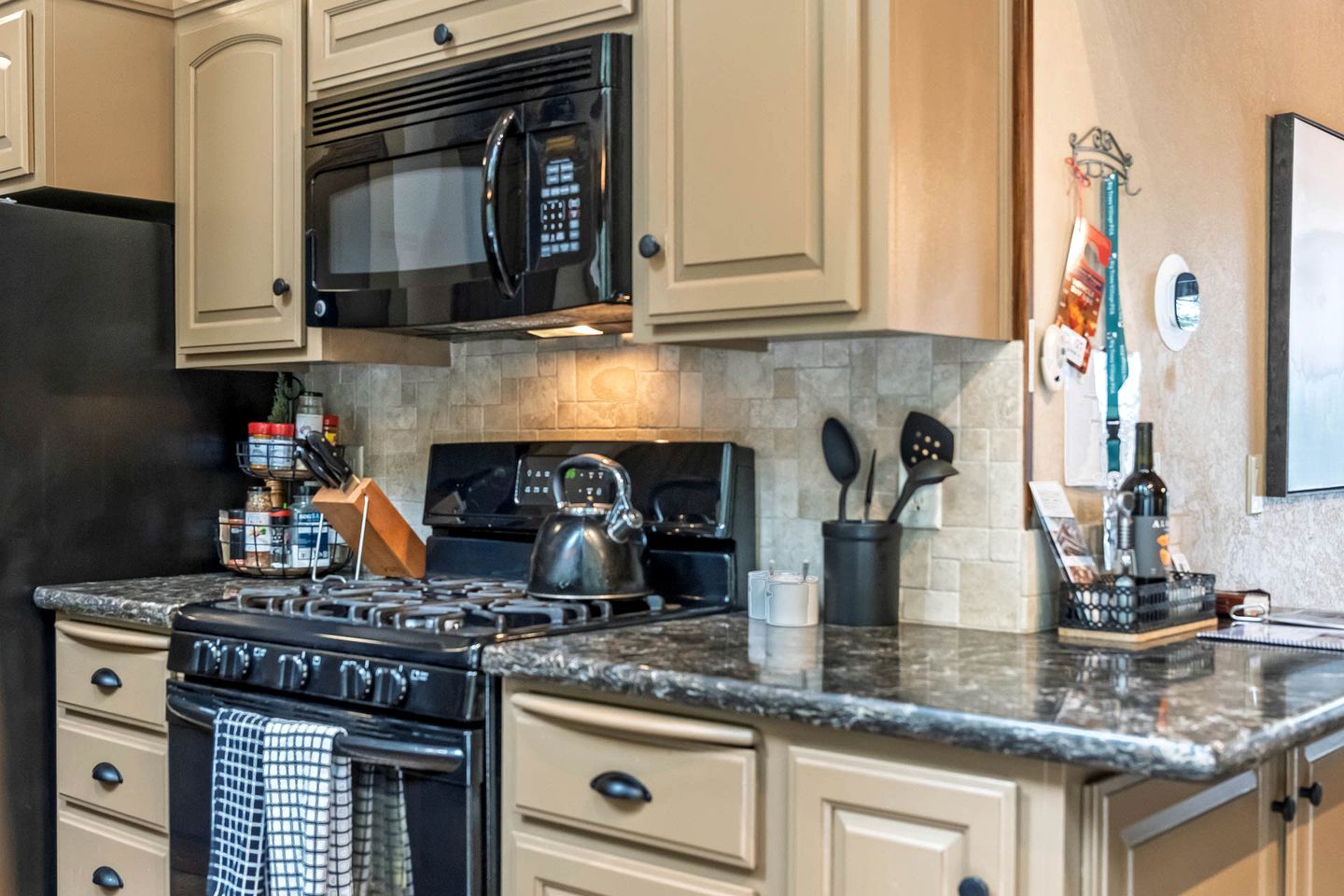 A kitchen with a stove, microwave, and various utensils.