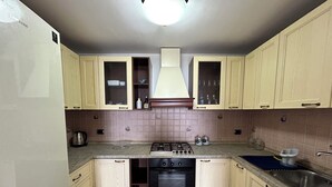 A kitchen with light-colored cabinets, a gas stove, an oven, and a sink.