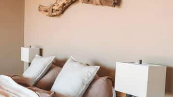 A bedroom with a bed, pillows, a hanging wooden piece, and bedside lamps.