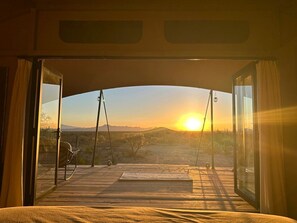 Una autocaravana oberta amb una vista del sol ponent sobre un paisatge desèrtic.