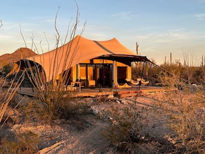 A desert tent with a covered porch and outdoor seating.