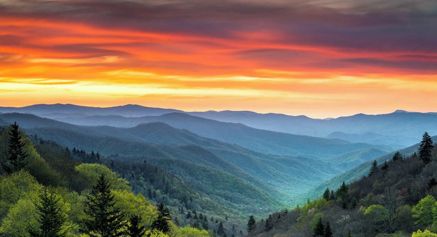A mountainous landscape with a valley and forested hills.