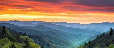 A mountainous landscape with a valley and forested hills.