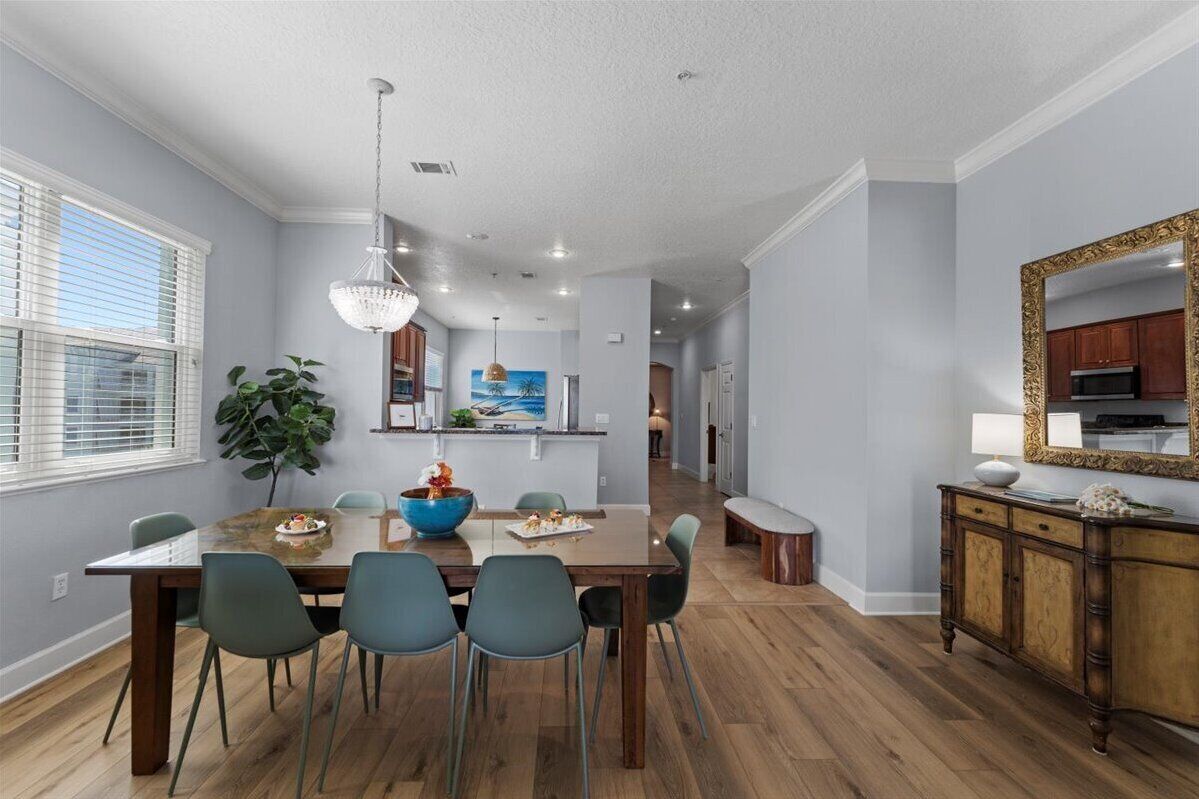 A dining area with a wooden table and chairs, a blue bowl, and a chandelier.