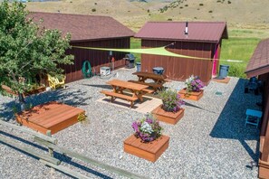 Eine Terrasse mit Holzbanken, Pflanzkästen mit Blumen, einem Grill und einer Überdachung.