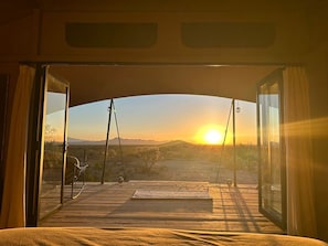 Ein Wohnmobil mit offener Bauweise, mit Blick auf einen Sonnenuntergang über einer Wüstenlandschaft.