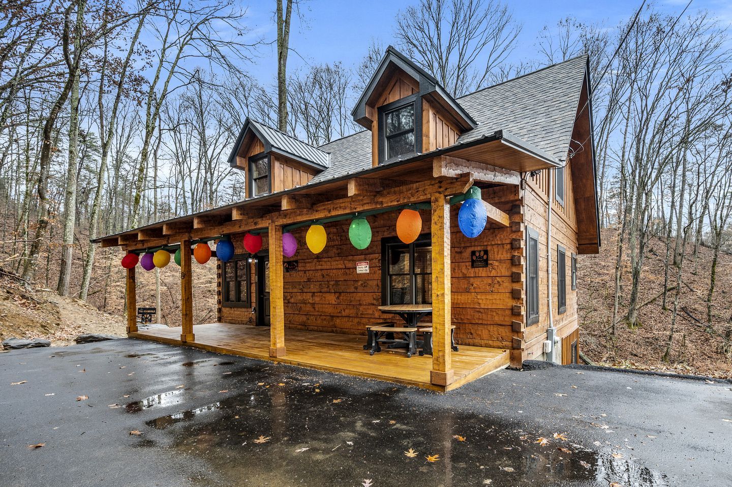 A wooden cabin with a covered porch and a dining area.