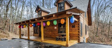 A wooden cabin with a covered porch and a dining area.