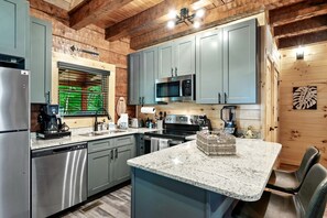 A modern kitchen with granite countertops, stainless steel appliances, and wooden paneling. - Delightful Cabin Amazing for Families with Private Porch in Tennessee (Sevierville)