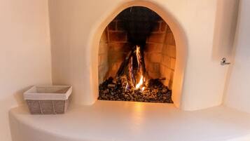 Une cheminée avec une arche en pierre, un manteau de cheminée blanc et un panier de bois de chauffage.