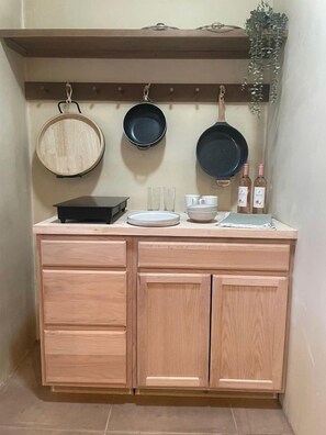 A compact kitchen with a wooden countertop, three hanging pans, a small sink, and a wine bottle. - Cozy Desert Casita with Stargazing Views near Sonoran Desert, Arizona (Marana)