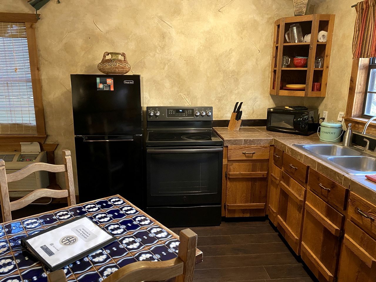 A compact kitchen with a refrigerator, oven, microwave, and wooden cabinets.