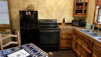 A compact kitchen with a refrigerator, oven, microwave, and wooden cabinets.