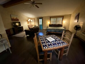 A cozy room with a dining table, chairs, a sofa, a bed, a TV, and a ceiling fan. - Eco-Friendly Cabin with Private Hot Tub for a Relaxing Getaway near Dallas, Texas (Bluff Dale)