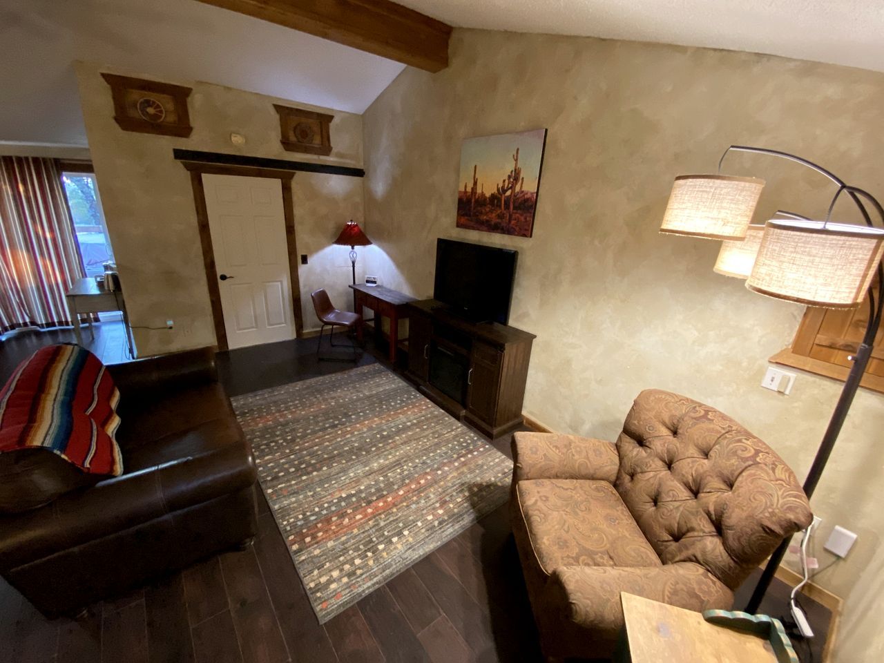 A living room with a sofa, a patterned rug, a television, and a lamp.