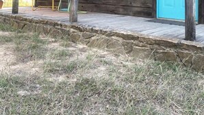Un bâtiment rustique en bois, doté d’une porte turquoise, d’un banc et d’une pancarte sur laquelle on peut lire : « Soyez gentils ».