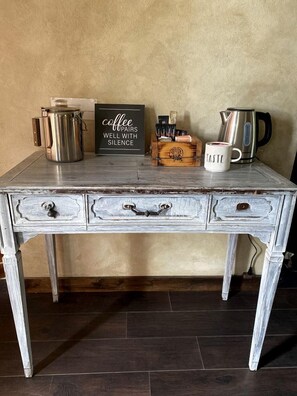 Una mesa de madera rústica con una cafetera, una taza y un letrero que dice 'el café combina bien con el silencio'.