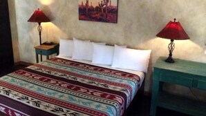 Un lit recouvert d’une couvre-lit à motifs, deux tables de chevet avec des lampes et un tableau accroché au mur.