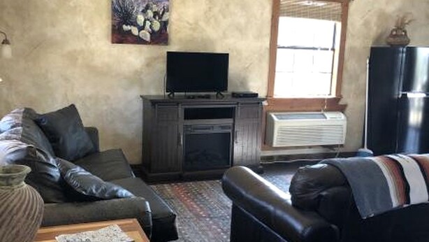 Un salon avec un canapé, une télévision, une cheminée et une fenêtre.