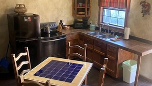 Une cuisine compacte comprenant une table à manger, des chaises en bois, un réfrigérateur, un four à micro-ondes et un placard.