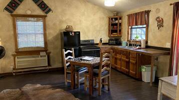 A rustic kitchen with wooden cabinets, a dining table, and a fur rug.