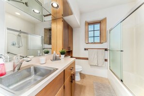 Een moderne badkamer met douche, wastafel, toilet en een raam.