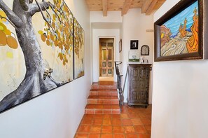 Ein Flur mit Treppe, einem großen Baumgemälde und einem gerahmten Kunstwerk an der Wand.