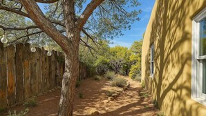 Un sendero que lleva a un edificio con una valla de madera y un árbol.