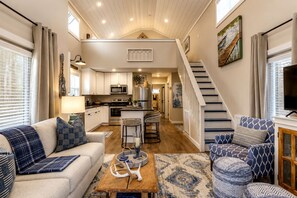 A spacious living area with a sofa, coffee table, and a staircase leading to an upper level. - Embrace Nature in this Cozy Cabin with Fire Pit in Monteagle, Tennessee (Monteagle)