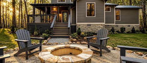 Uma cabana com um poço de fogueira de pedra, duas cadeiras Adirondack e um deck com escadas que levam à entrada.