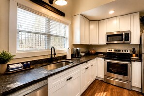A modern kitchen with white cabinets, a stainless steel sink, a built-in microwave, and an oven. - Embrace Nature in this Cozy Cabin with Fire Pit in Monteagle, Tennessee (Monteagle)