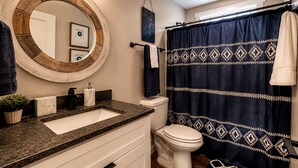 A bathroom with a round mirror, a sink, a toilet, and a shower curtain. - Embrace Nature in this Cozy Cabin with Fire Pit in Monteagle, Tennessee (Monteagle)