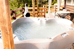 Een hottub op een houten terras, met uitzicht op bomen.