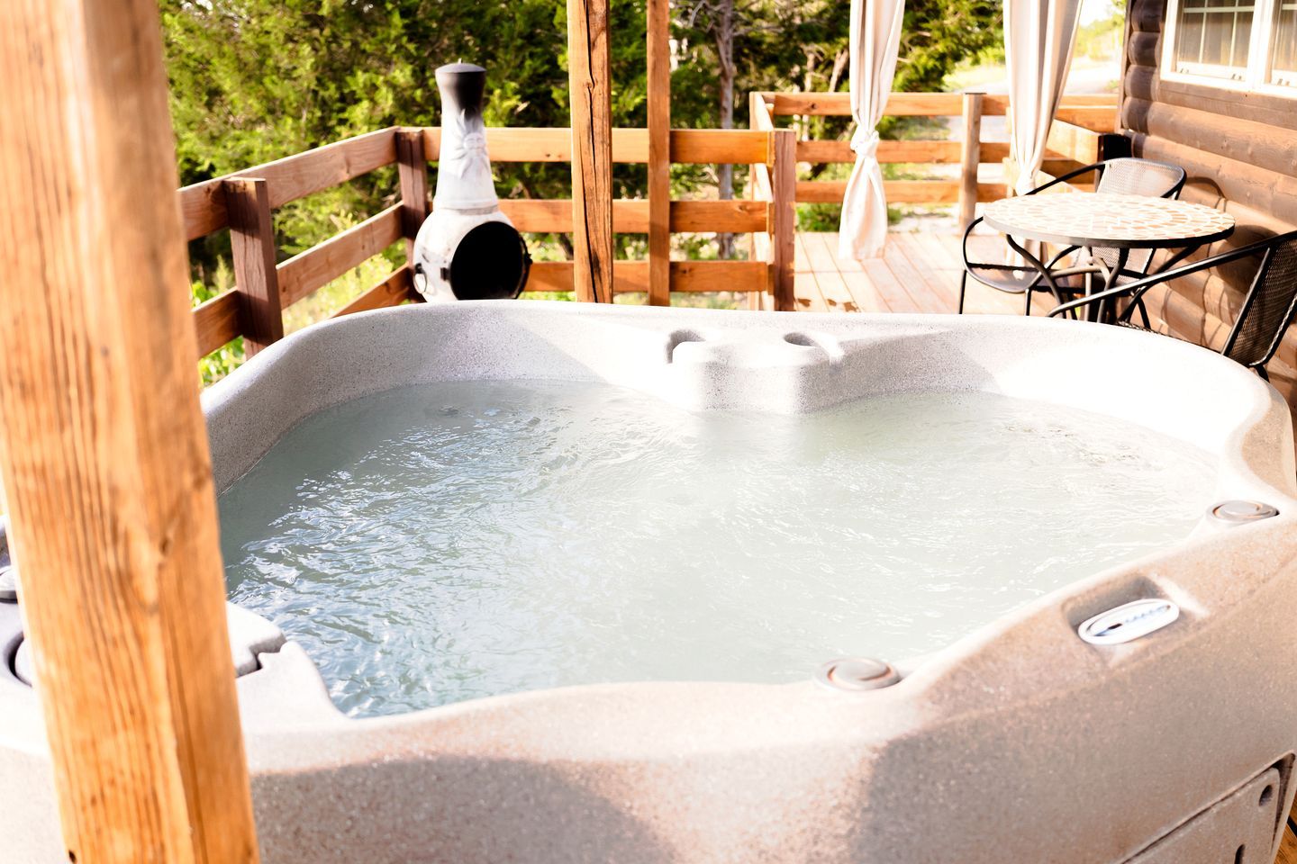 Un bain à remous sur une terrasse en bois, avec vue sur les arbres.