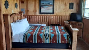 A wooden room with a bed, a television, and a window.