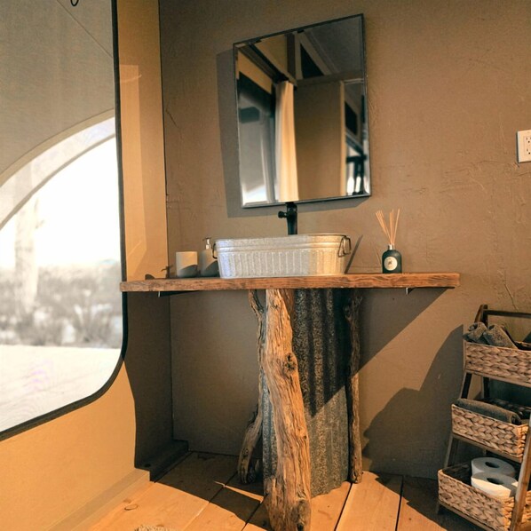 Un baño con tocador de madera, un espejo y una ventana.